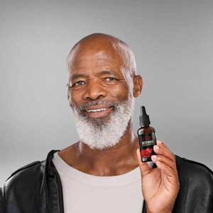 Man in his sixties holding a bottle of Sugar Defender drops
